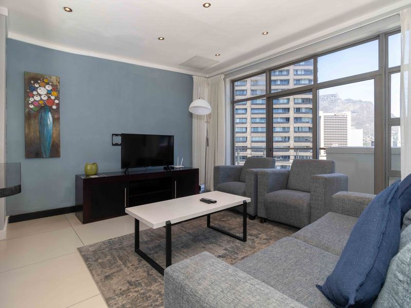 A bright living room featuring large floor-to-ceiling windows with city views, tiled flooring, and recessed downlighting.