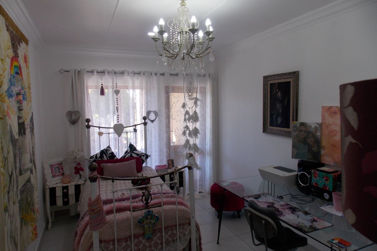 A bedroom featuring tiled flooring, crown molding, and a central chandelier, with access to natural light through a window.