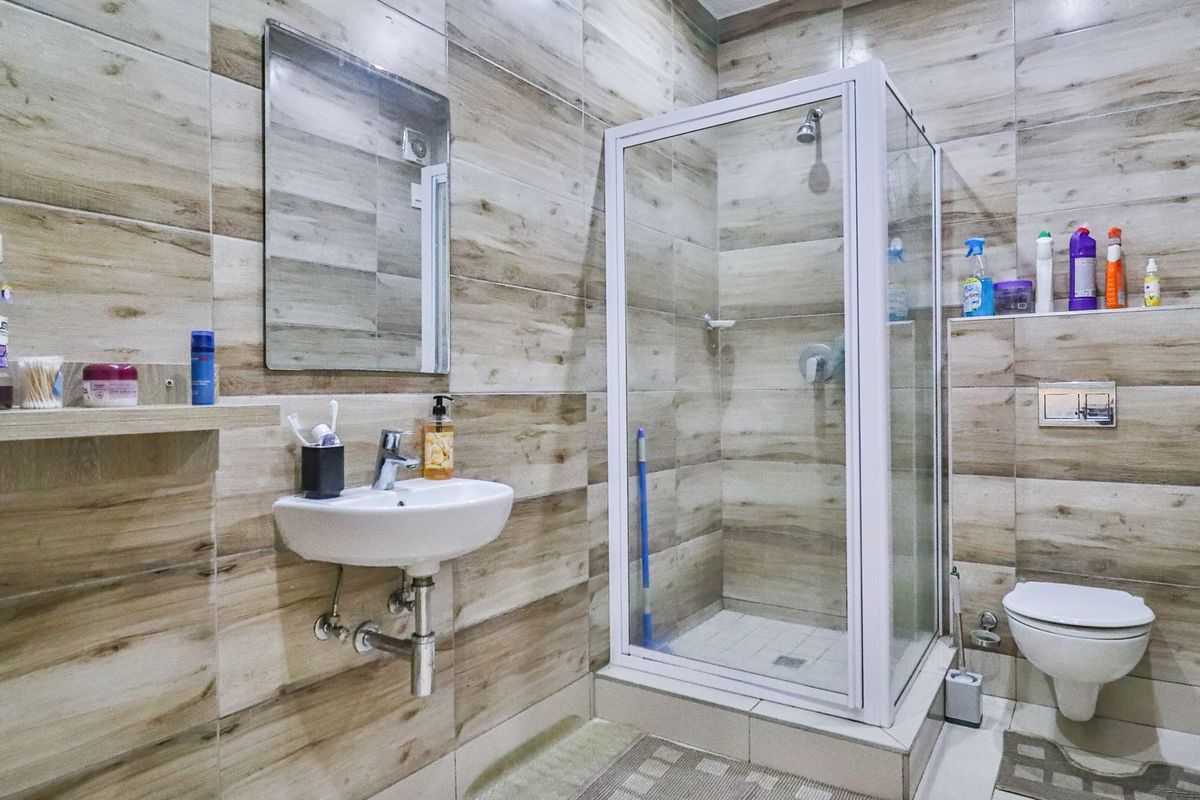 Modern bathroom featuring floor-to-ceiling wood-look tiling, a wall-mounted basin, a glass-enclosed shower, and a wall-hung toilet with a concealed cistern.