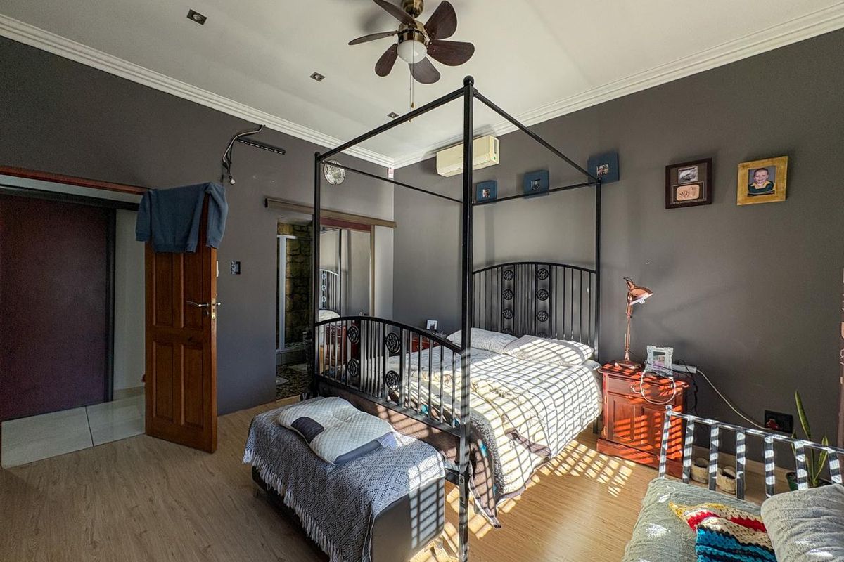 A spacious bedroom featuring laminate flooring, recessed lighting, a ceiling fan, and a wall-mounted split-system air conditioner.
