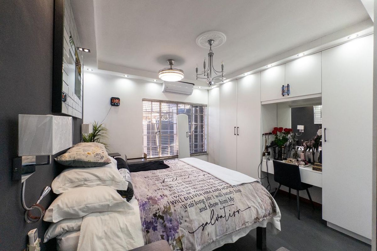 A well-appointed bedroom featuring extensive built-in cabinetry with an integrated vanity, modern lighting, and a split-system air conditioner.