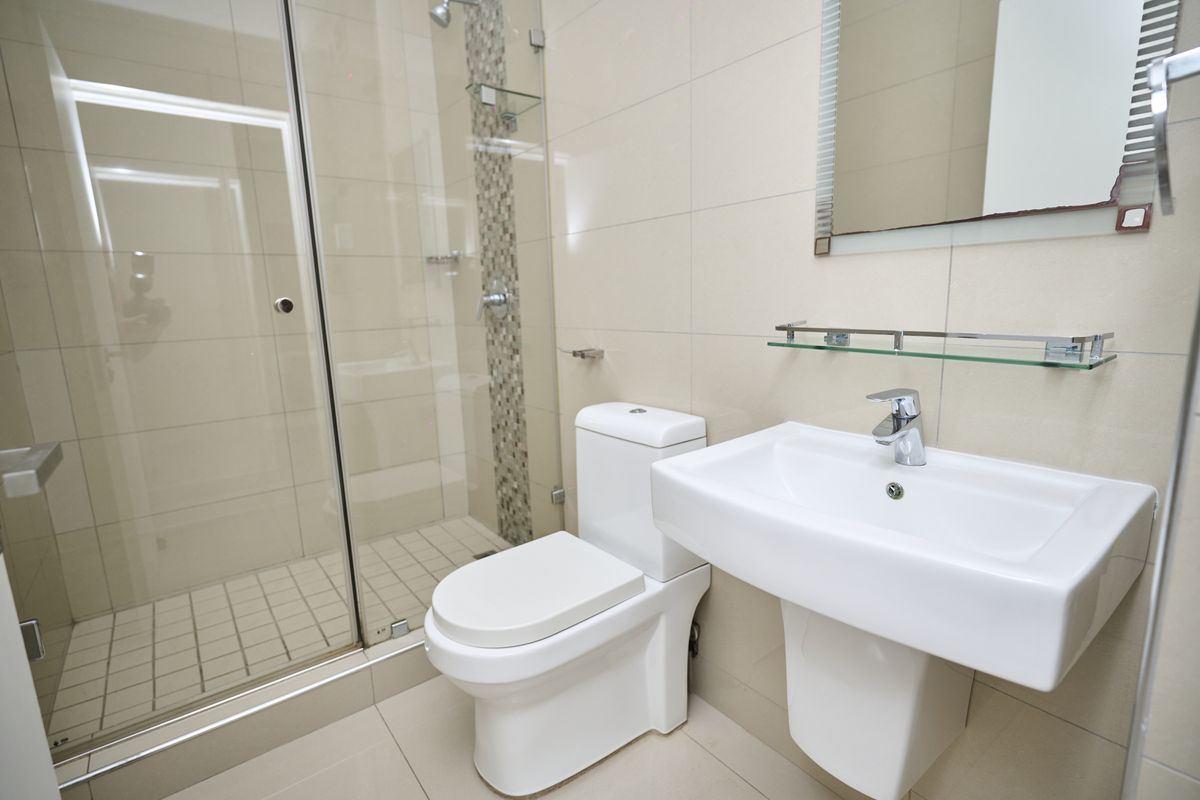 Modern bathroom featuring a glass-enclosed shower, wall-mounted basin, and neutral tiled finishes throughout.