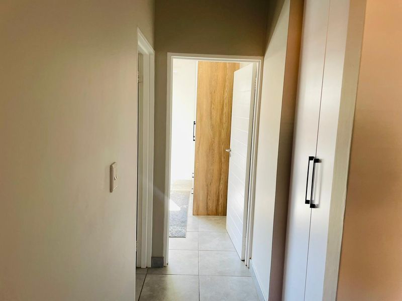 A clean, modern hallway featuring neutral floor tiles and built-in cabinetry, providing a seamless transition between living spaces.