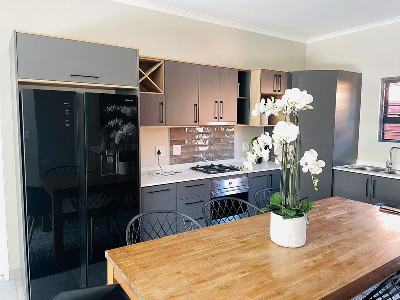 Modern kitchen featuring grey cabinetry, light wood accents, subway tile backsplash, built-in oven, gas hob, and integrated sink.