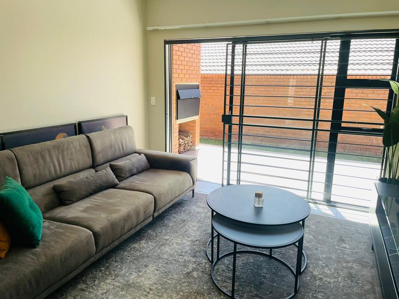 Living room featuring large sliding glass doors that open onto a private patio with a built-in brick fireplace.