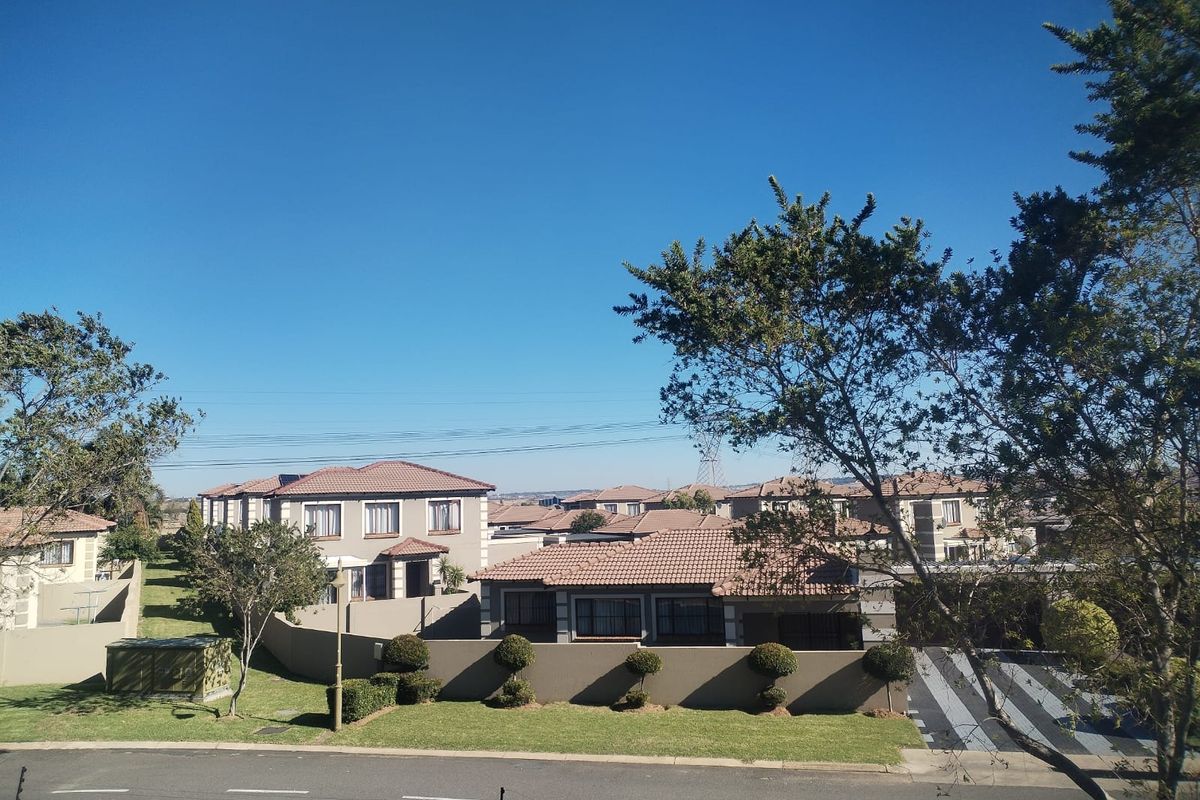 An elevated view overlooking a residential neighborhood featuring well-maintained homes with tiled roofs, boundary walls, and manicured lawns.