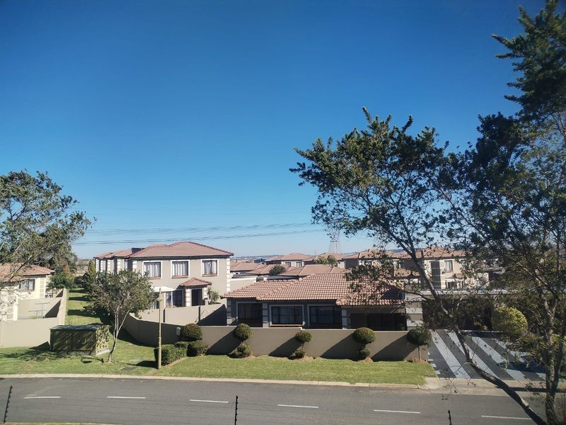 An elevated view overlooking a residential neighborhood featuring well-maintained homes with tiled roofs, boundary walls, and manicured lawns.