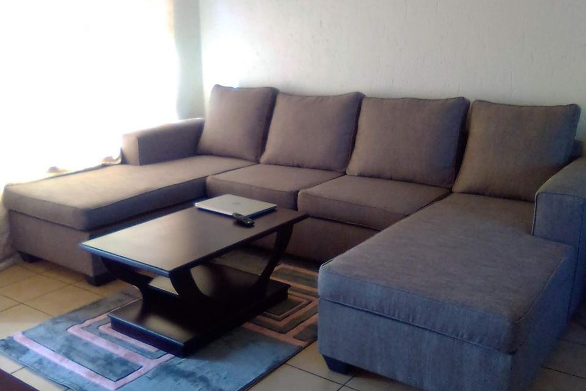 A living room area featuring neutral tiled flooring and natural light from a window.