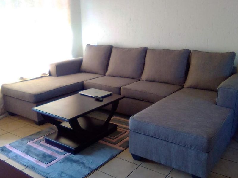 A living room area featuring neutral tiled flooring and natural light from a window.