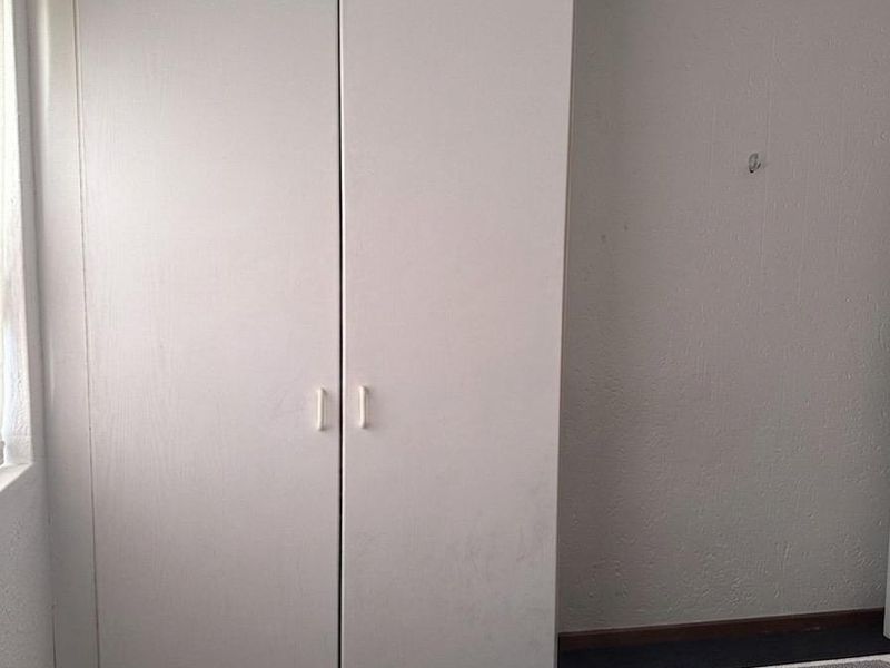 A bedroom featuring a built-in wardrobe with white doors and carpeted flooring.