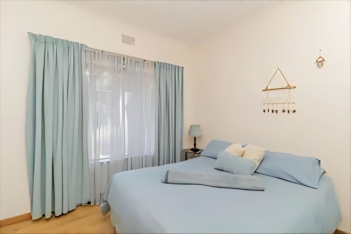 A bedroom featuring light-toned flooring, neutral walls, and floor-to-ceiling curtains covering the window area.