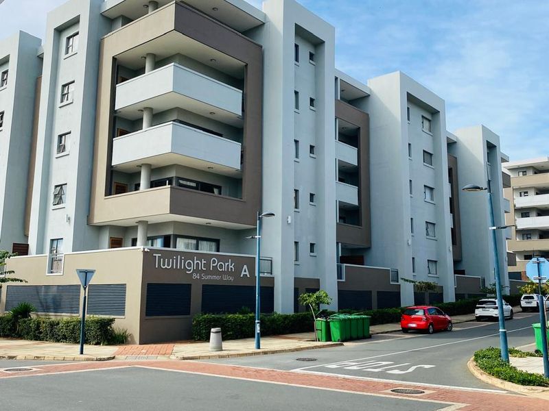 Street view of the Twilight Park apartment complex, showcasing the modern multi-story building facade, balconies, and surrounding paved street infrastructure.