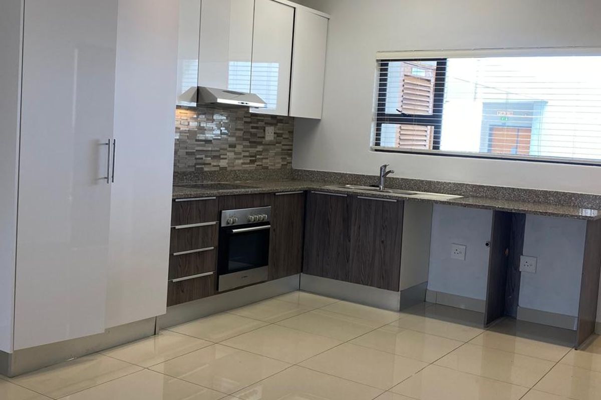 Modern kitchen featuring high-gloss white upper cabinetry, wood-grain lower cabinets, granite countertops, built-in oven, extractor fan, and polished porcelain floor tiles.