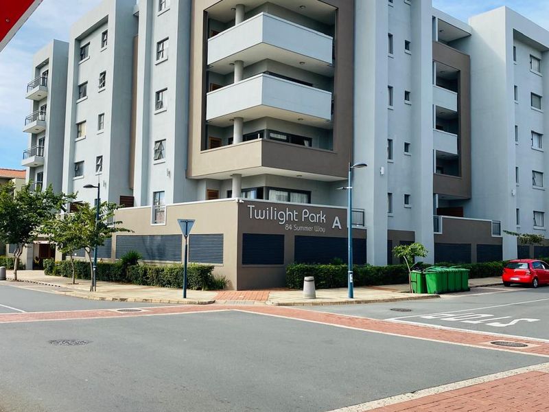Exterior view of the Twilight Park apartment complex, showcasing the modern multi-story building facade, balconies, and street-level entrance.