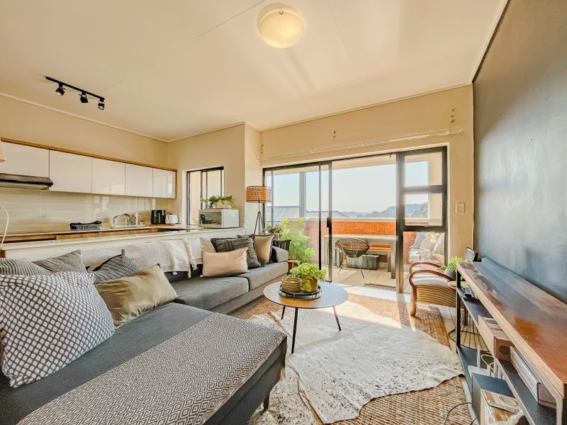 Open plan living area featuring a modern kitchen with built-in cabinetry and seamless access to a private balcony through large sliding glass doors.