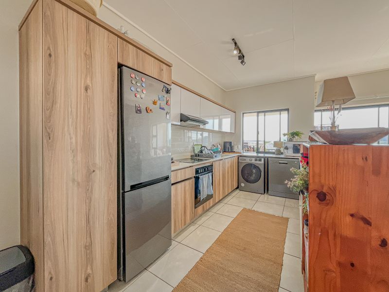 A functional kitchen featuring wood-look cabinetry, tiled flooring, a built-in oven and hob, and a tiled backsplash, offering a clean and practical workspace.