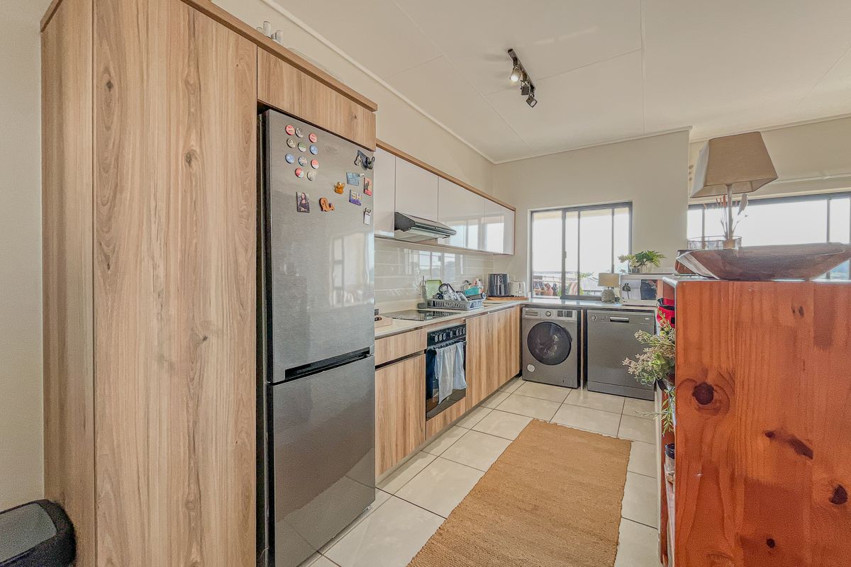 A functional kitchen featuring wood-look cabinetry, tiled flooring, a built-in oven and hob, and a tiled backsplash, offering a clean and practical workspace.