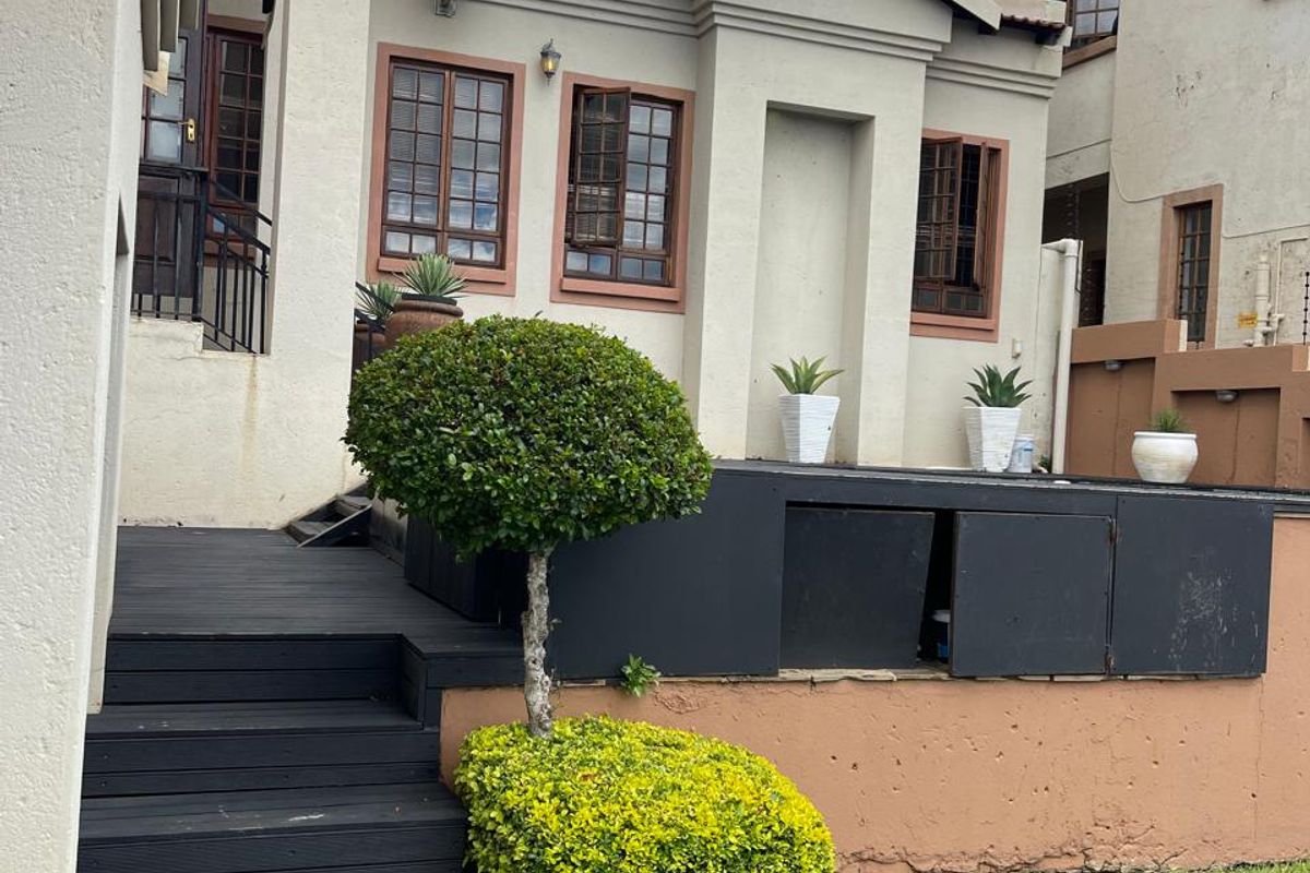 Rear exterior view of the property featuring a raised timber deck, landscaped garden area, and traditional window frames.