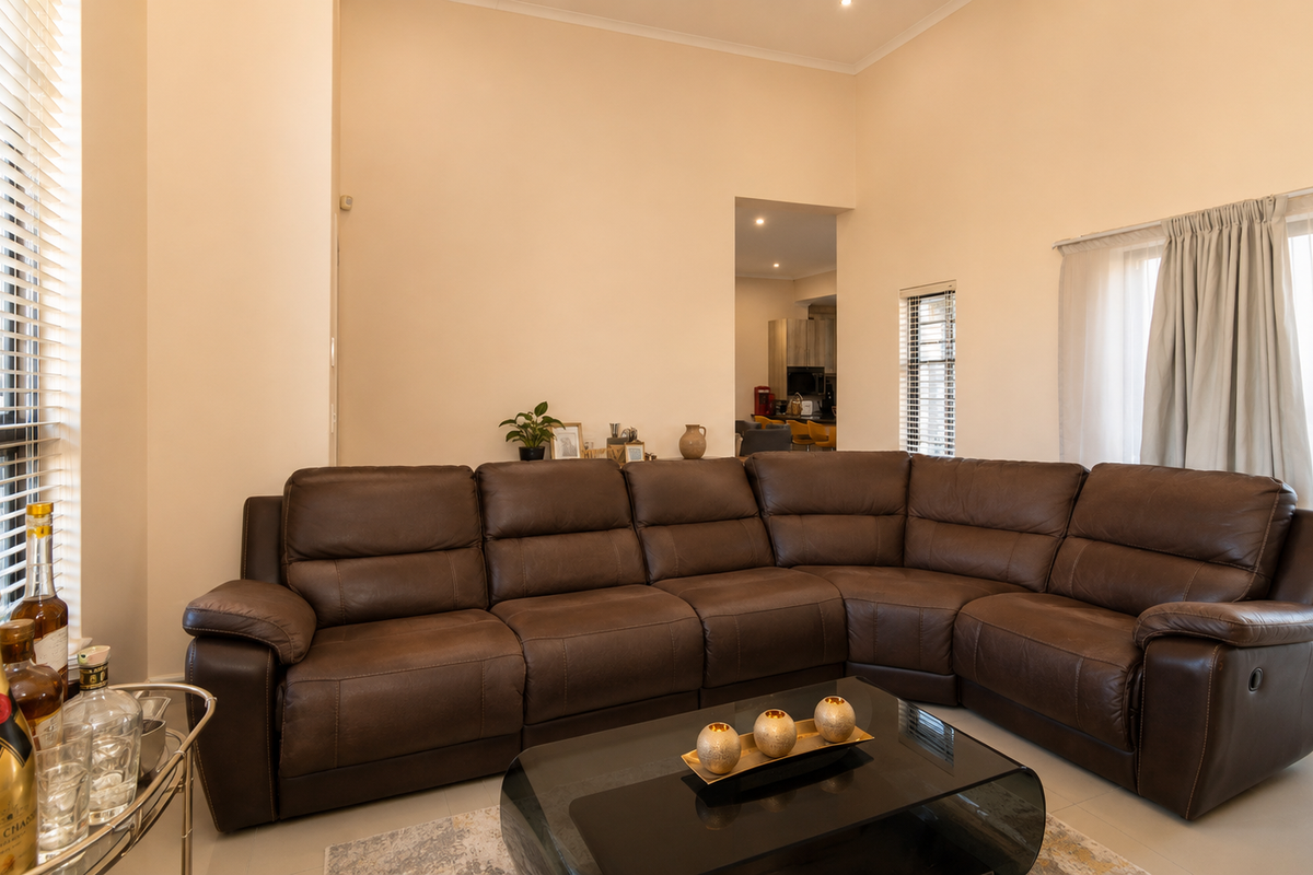 Spacious living room featuring high ceilings, large windows with blinds, and direct access to an outdoor area through sliding glass doors.