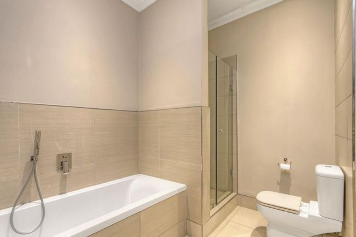 Modern bathroom featuring a built-in bathtub with handheld shower attachment, a separate glass-enclosed shower, and a white toilet.