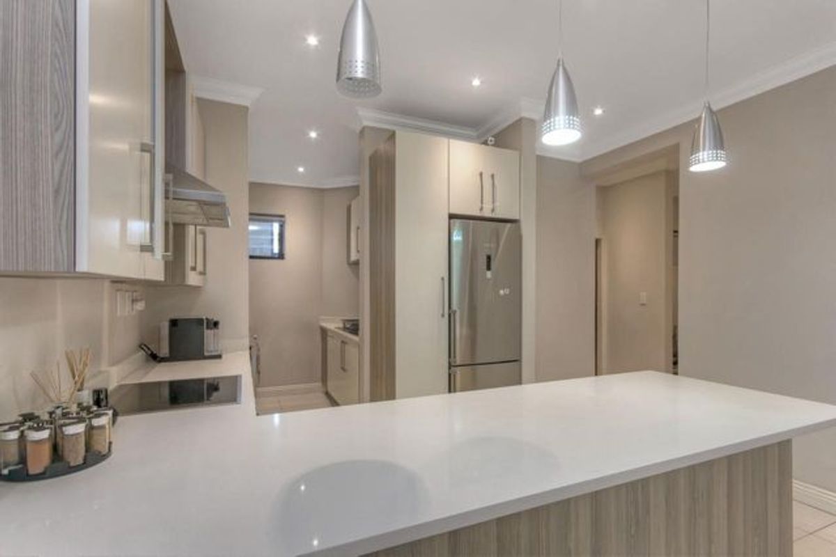 Modern kitchen featuring a breakfast bar, stone countertops, built-in cabinetry, and integrated stainless steel appliances with recessed lighting.