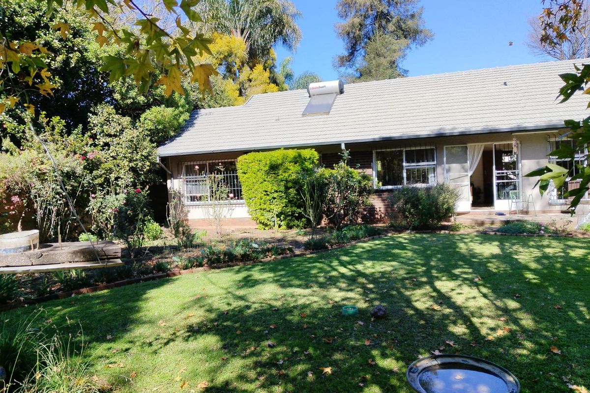 A view of the rear exterior of the house featuring a tiled roof, solar water heater, and a spacious garden with established landscaping.