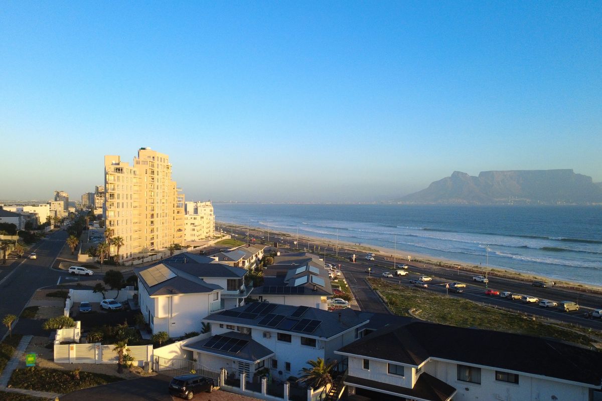 Elevated coastal view overlooking the ocean, Table Mountain, and surrounding residential neighborhood from an apartment perspective.