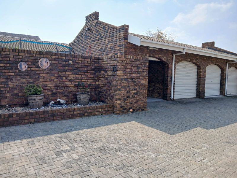 Front exterior view of the townhouse featuring a face-brick facade, paved driveway, and multiple garage doors.