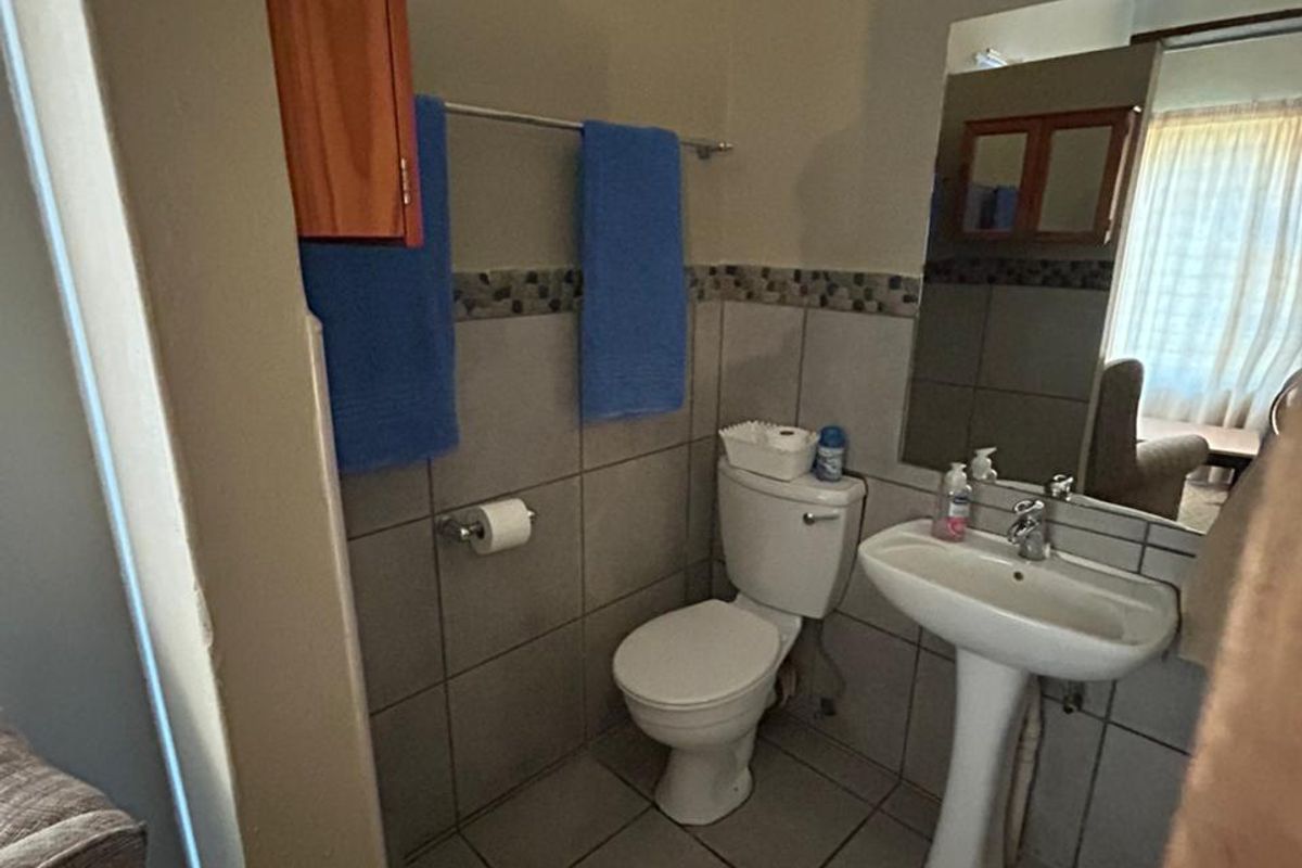 A functional bathroom featuring a pedestal basin, toilet, and tiled walls with a decorative border.