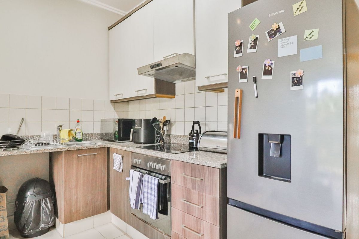 A functional kitchen featuring granite countertops, built-in oven with hob, extractor fan, and ample cabinetry for storage.