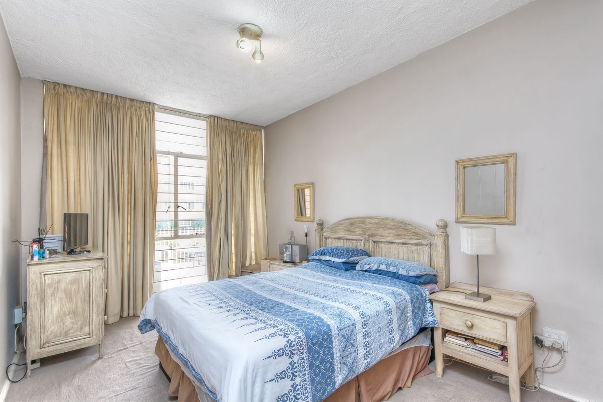 A bedroom featuring carpeted flooring, a large window with floor-to-ceiling curtains, and a central ceiling light fixture.