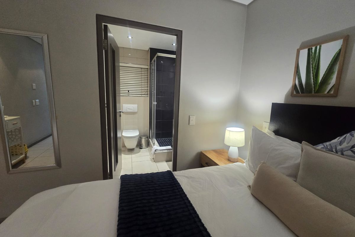 A well-maintained bedroom featuring an en-suite bathroom with a glass-enclosed shower and modern fixtures.