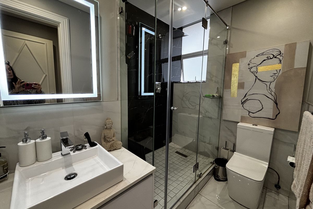 Modern bathroom featuring a vessel sink vanity, a glass-enclosed walk-in shower with dark marble-style tiling, and a contemporary toilet.
