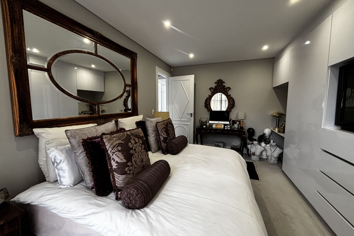 A well-appointed bedroom featuring recessed ceiling lighting, built-in high-gloss cabinetry, and neutral wall finishes.