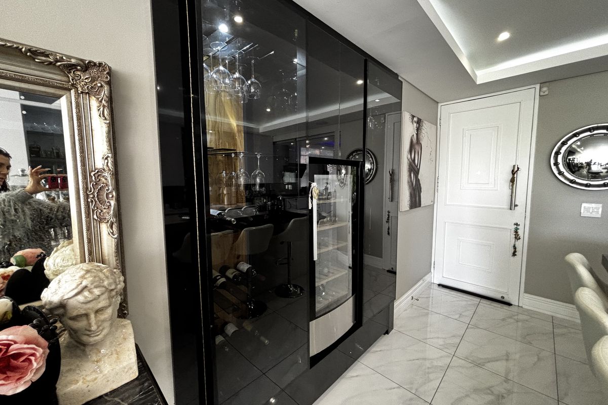 Modern interior space featuring a sleek, built-in black glass wine display cabinet with integrated lighting and a contemporary white panelled door.