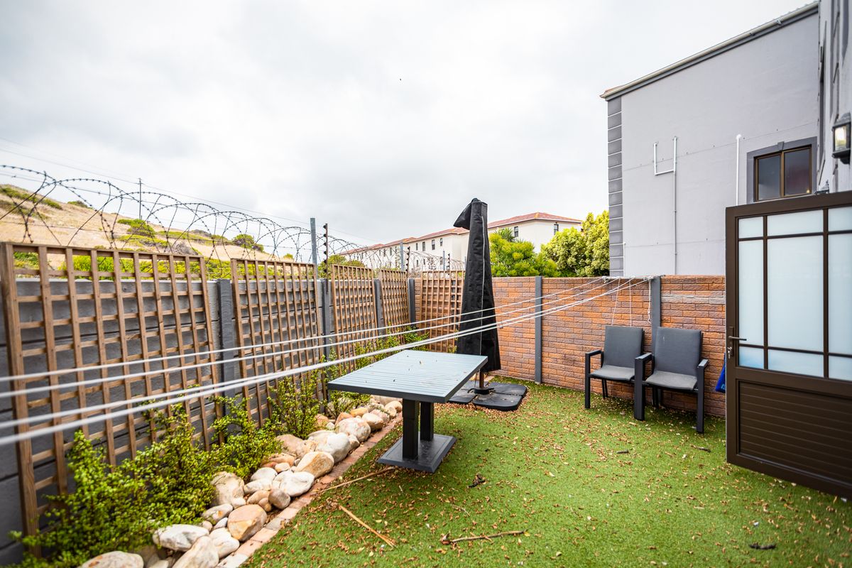 A private rear courtyard featuring artificial turf, brick boundary walls, timber trellis fencing, and a fixed washing line.