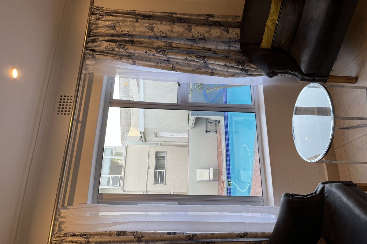A view from an interior room looking out towards a private swimming pool area with paved surround.