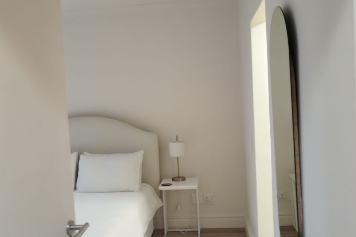 A clean and bright bedroom featuring light wood-look flooring and neutral wall finishes, viewed from the doorway.