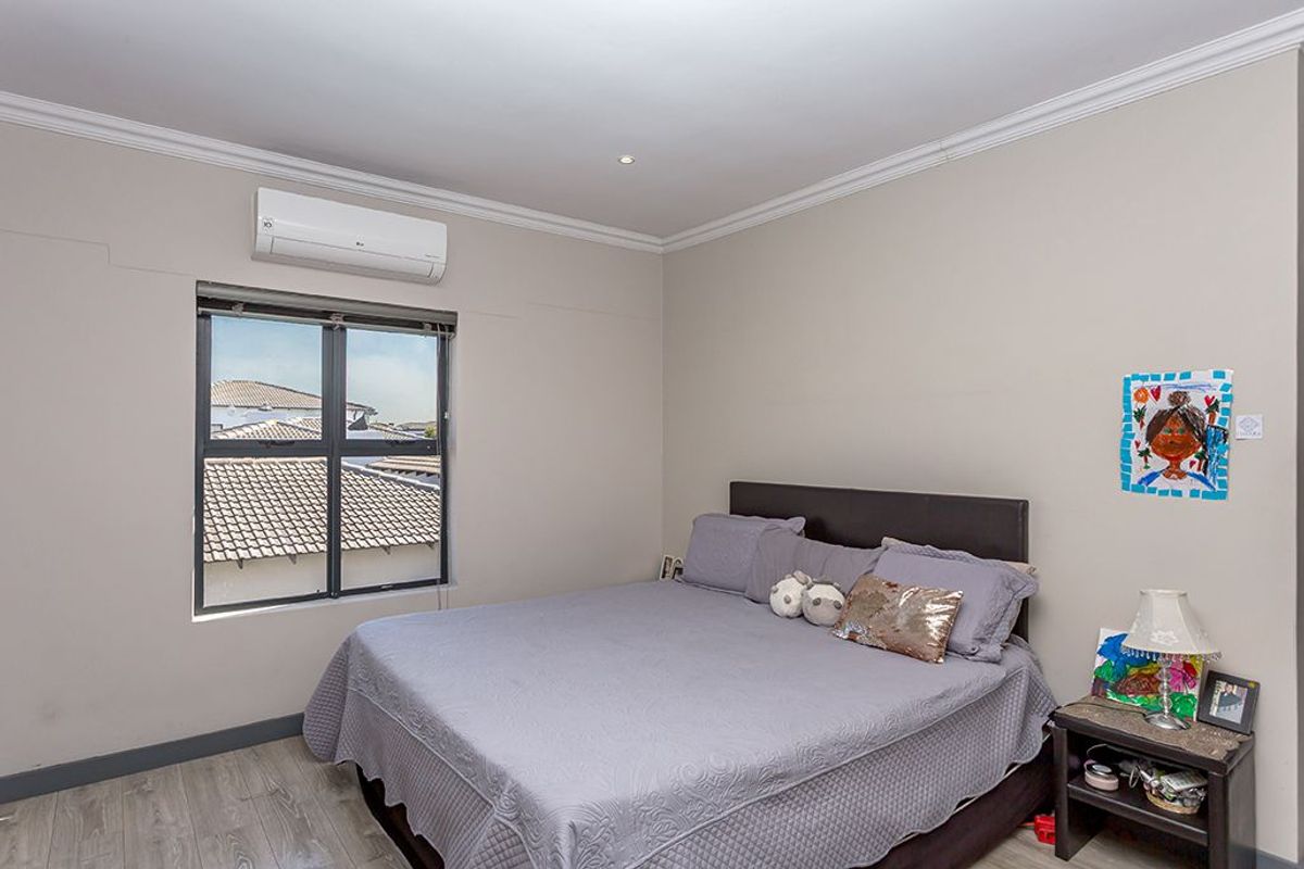 A bedroom featuring laminate flooring, crown molding, and a wall-mounted air conditioning unit.