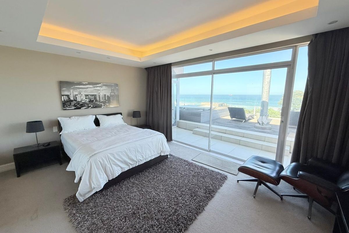 Spacious bedroom featuring a recessed ceiling with ambient lighting and large sliding glass doors opening onto a private deck with ocean views.