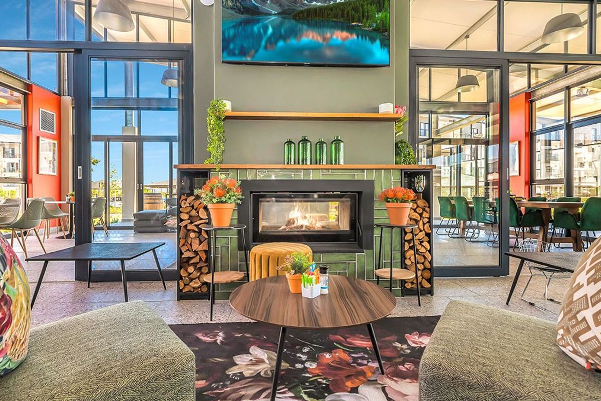 A modern, well-lit living area featuring a built-in fireplace with tiled surround, large glass sliding doors, and high ceilings in a contemporary apartment setting.