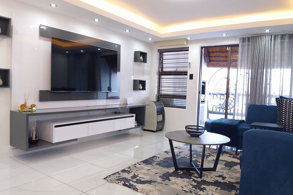 Modern living room featuring high-gloss cabinetry, recessed ceiling lighting, polished floor tiles, and direct access to an outdoor patio area.