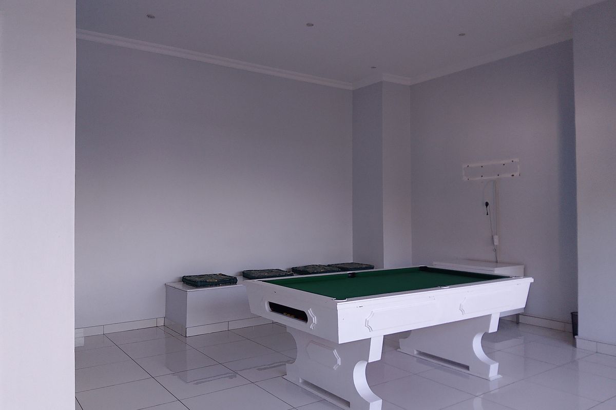 A spacious room featuring tiled flooring, recessed ceiling lighting, and a built-in bench, currently utilized as a recreational space.