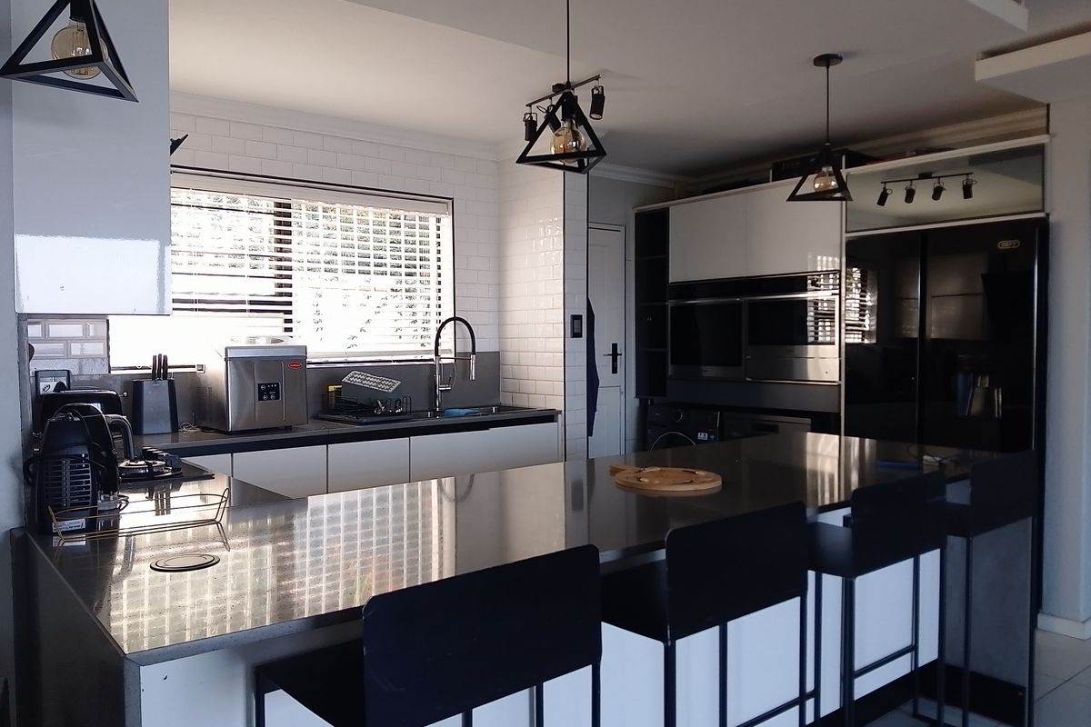 Modern kitchen featuring a large central island with stone countertops, built-in oven, integrated cabinetry, and subway tile backsplash.