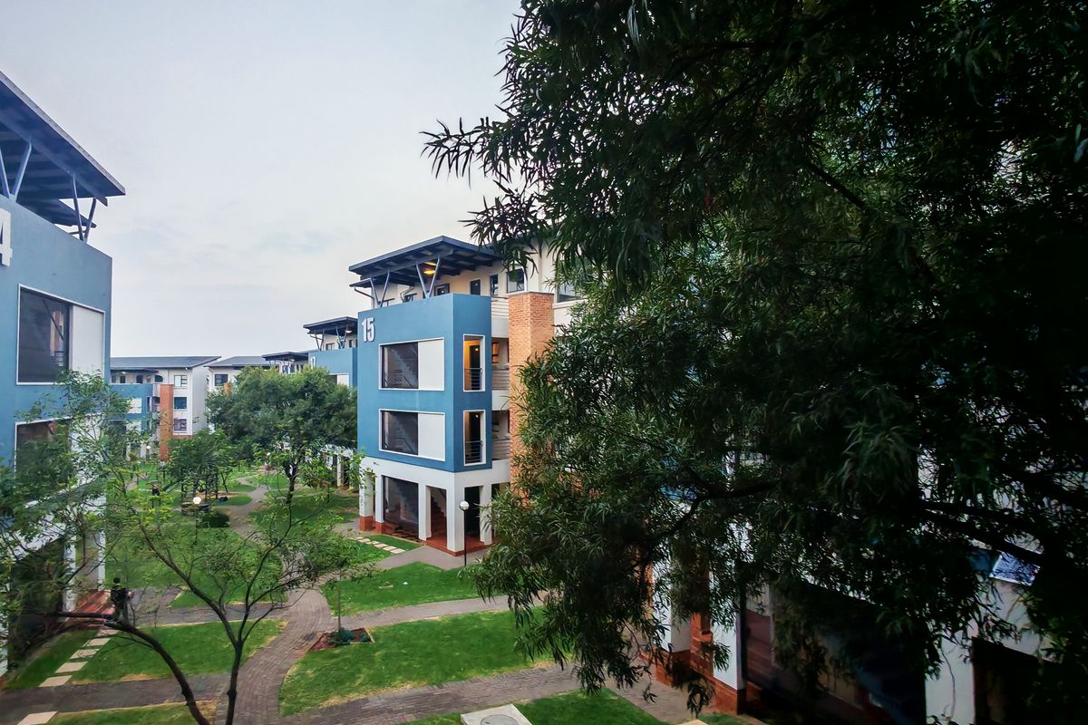 Elevated view of a modern apartment complex courtyard featuring landscaped gardens, paved walkways, and contemporary multi-story residential buildings.