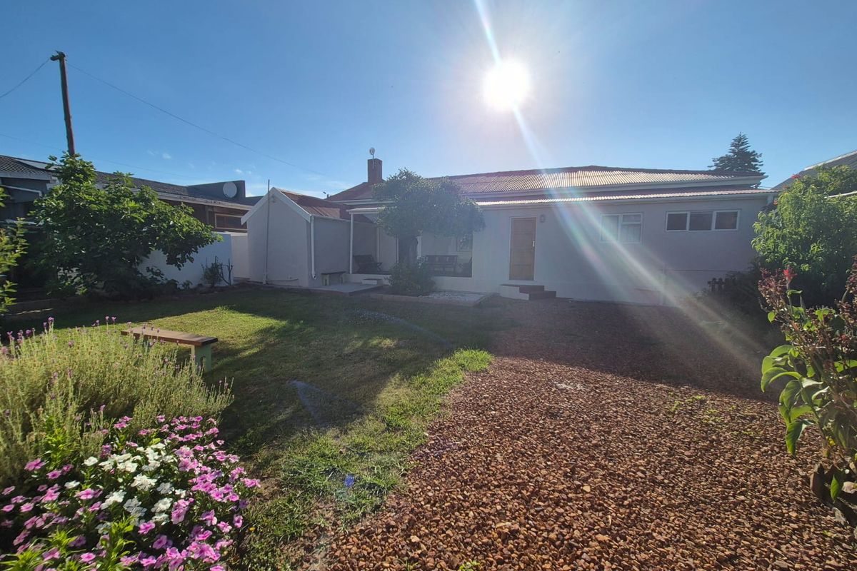 A view of the rear exterior of the house featuring a garden area with gravel landscaping and a lawn.