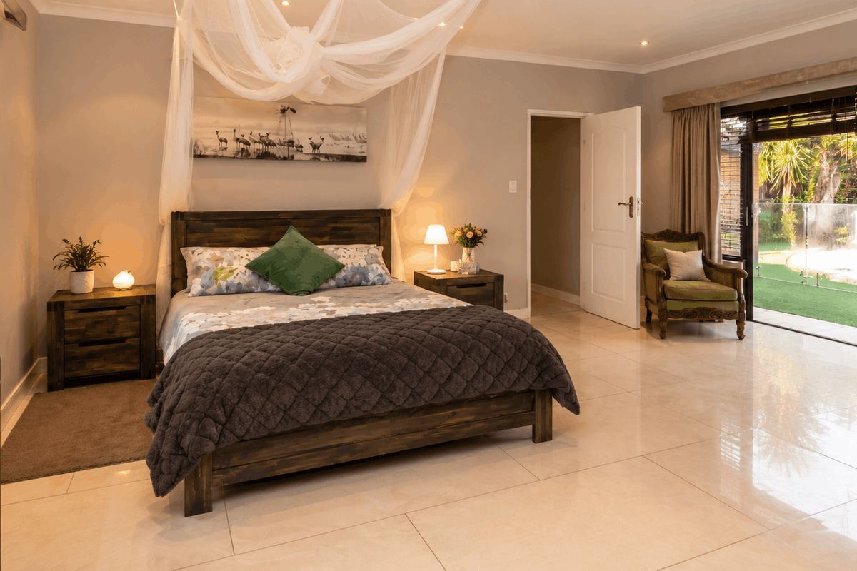 Spacious bedroom featuring large format floor tiles, recessed downlighting, and sliding glass doors providing direct access to the outdoor garden area.
