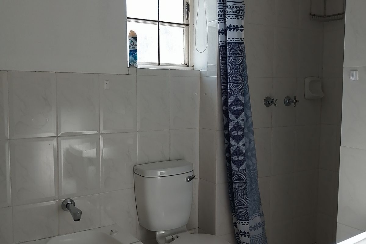 A functional bathroom featuring a built-in bathtub, a separate shower enclosure with a curtain, and a standard toilet.