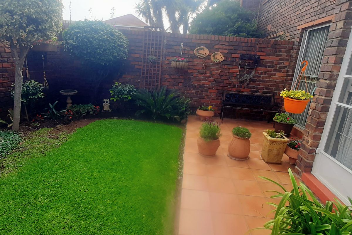 A private rear garden featuring a paved patio area, established lawn, and perimeter brick walling, providing a quiet outdoor space.