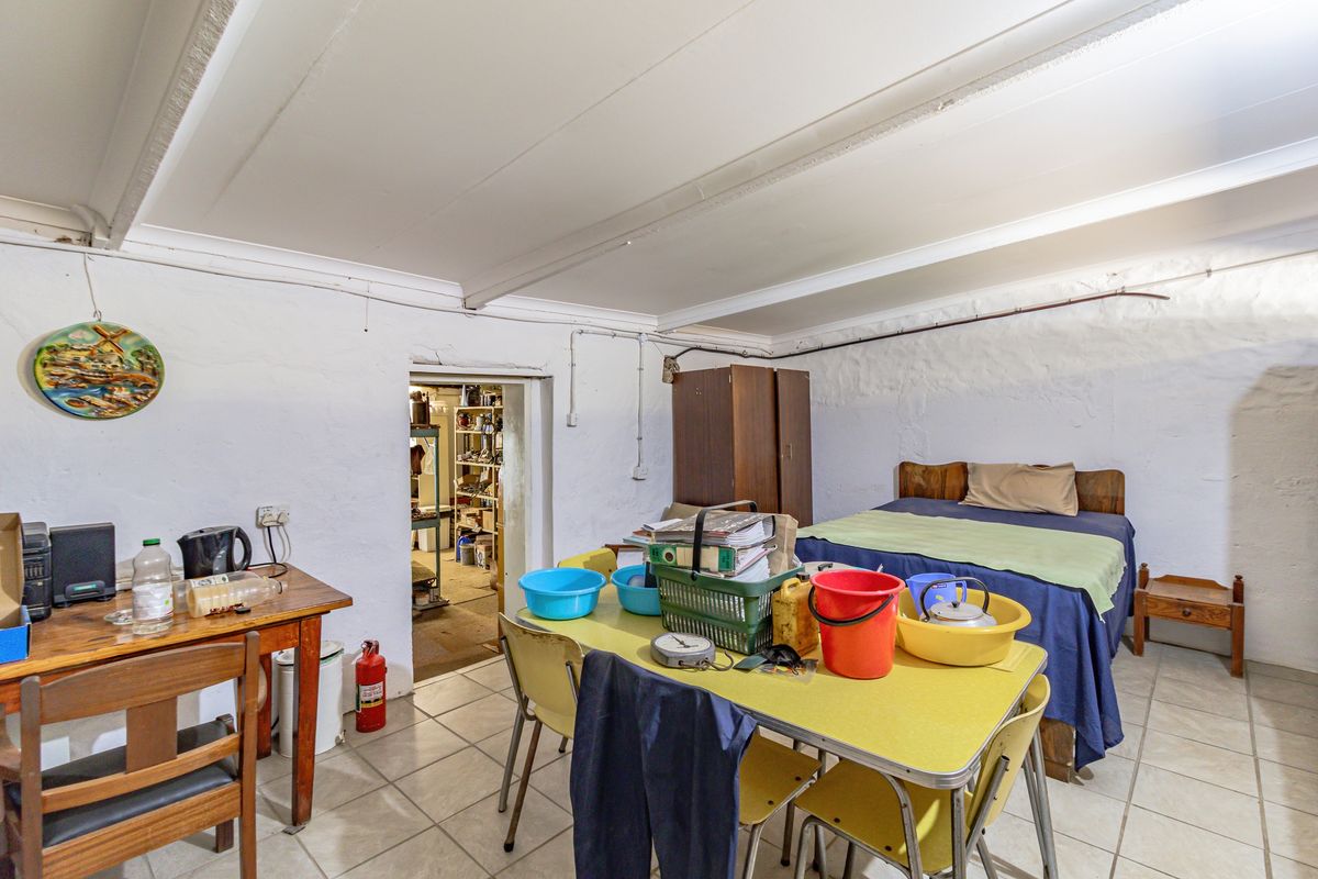 A bedroom space featuring tiled flooring and exposed ceiling beams, with access to an adjacent utility or storage area.